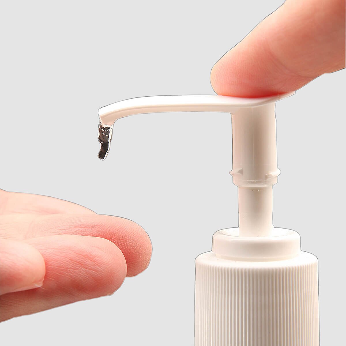 Close-up of the attachable pump dispensing ethanol-based sanitizer into a fingertip.
