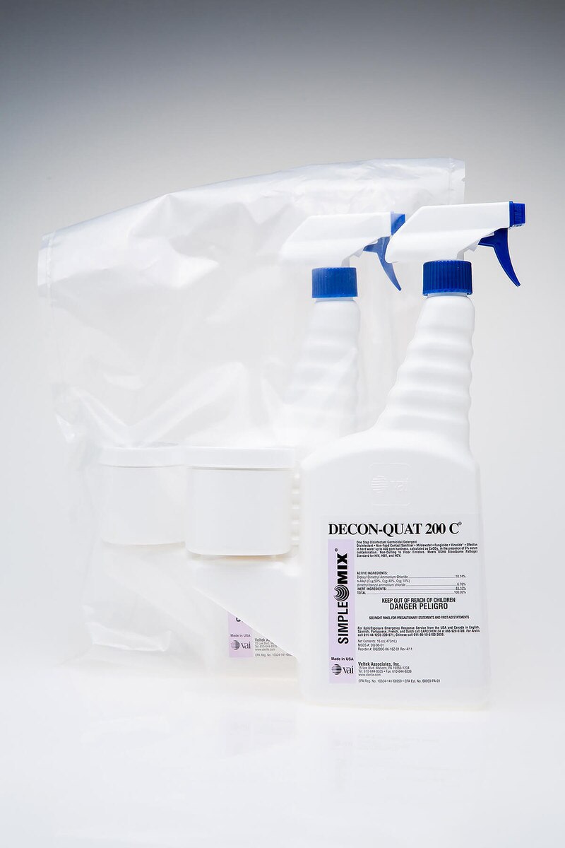 Two Sterile DECON-QUAT 200C 16oz trigger spray bottles, one sealed in a clear sterile bag and one unbagged in front, showing the blue trigger heads and white measuring chambers.