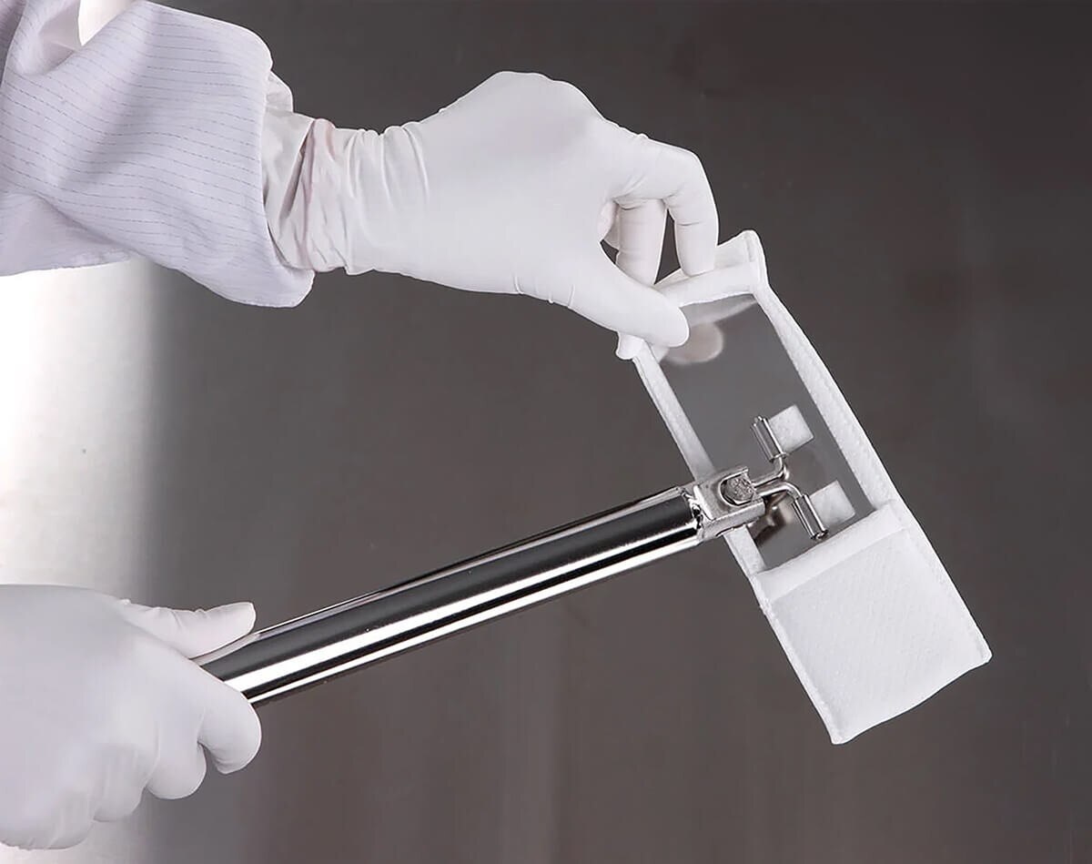 Gloved hands attaching an EasyReach bound-edge poly mop pad onto a stainless steel isolator mop head.